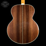 The back of an acoustic guitar with a rich, dark brown wood grain finish, featuring a white binding edge and a light-colored neck visible at the top, set against a solid black background.