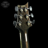 Close-up of the headstock of a guitar against a black background, showing six tuning pegs and a dark glittery finish. A Tone Shop watermark is visible in the top left corner.
