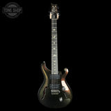 A dark electric guitar with a metallic bronze-to-black gradient finish, featuring gold bird inlays on the fretboard and a white headstock, shown against a solid black background.