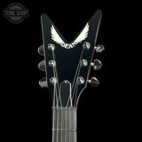 Close-up of the headstock of a Dean electric guitar against a black background, featuring the Dean wing logo and chrome tuning pegs.