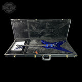 A blue electric guitar displayed inside an open black hard case with black foam lining, photographed against a solid black background. A Tone Shop watermark is visible in the top-left corner.