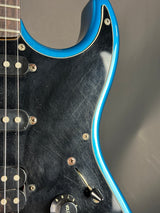 Close-up of a guitar with a blue pickguard and visible strings.