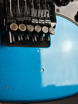 Close-up of a blue electric guitar with a focus on the neck and fretboard.