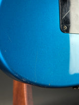 Close-up of a blue guitar with visible scratches on the body