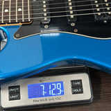Blue electric guitar on a digital scale displaying weight
