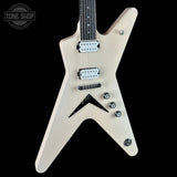 An electric guitar with a distinctive angular body in a metallic champagne gold finish, featuring white humbucker pickups and black hardware, shown against a solid black background.