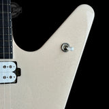 Close-up of a V-shaped electric guitar body in a champagne glitter finish, featuring a silver toggle switch and a black pickup against a black background.