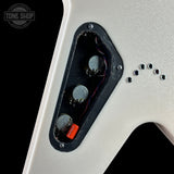 Close-up of a guitar body showing the back of a silver-finish instrument with a black control cavity, three silver knobs, exposed wiring, and a small orange component. A Tone Shop watermark appears in the upper left corner.