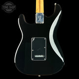 Close-up of the back of a black electric guitar body with a maple neck, chrome hardware, and a white pickguard on a black background.