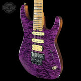 Purple electric guitar with a wooden neck on a black background, featuring 'Tone Shop' branding.