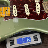 Green electric guitar on a digital scale displaying weight.