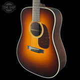 Acoustic guitar with a sunburst finish on a black background, featuring the Tone Shop logo.