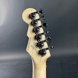 Guitar headstock with tuning pegs on a dark background