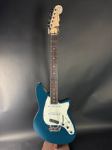 Blue electric guitar on a reflective black surface
