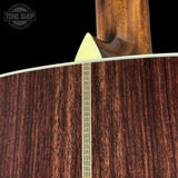 Close-up of a guitar's wooden finish with a brand logo in the corner.