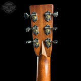 Close-up of the headstock of a wooden acoustic guitar against a solid black background, showing six tuning pegs and a Tone Shop watermark in the top left corner.