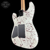 White electric guitar with red splatter design on a black background, featuring the Tone Shop logo.