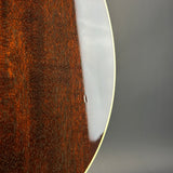 Close-up detail of an acoustic guitar's glossy brown wood backplate and white edge trim against a neutral gray background.