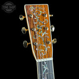 Close-up of a guitar headstock with intricate design on a black background