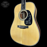 Acoustic guitar with a decorative pickguard on a black background, featuring the 'Tone Shop' logo.