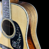 Close-up of an acoustic guitar with a decorative pickguard on a black background