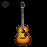 Acoustic guitar with a sunburst finish on a black background, featuring the Tone Shop logo.