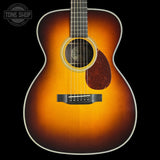 Acoustic guitar with a sunburst finish on a black background, featuring the Tone Shop logo.