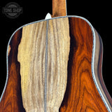 Close-up of an acoustic guitar's wooden body with a visible brand logo in the corner.