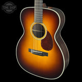 Acoustic guitar with a sunburst finish on a black background, featuring the Tone Shop logo.