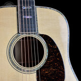 Close-up of an acoustic guitar with a focus on the soundhole and strings against a black background.