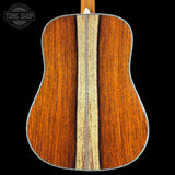 Back of a wooden acoustic guitar with a visible brand logo in the corner.