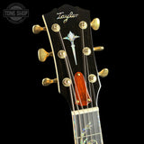 Taylor guitar headstock with decorative inlay on a black background