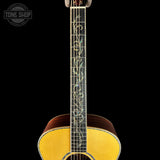 Acoustic guitar with decorative inlay on a black background, featuring 'Tone Shop' branding.