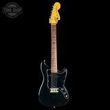 Black electric guitar with a yellow pickguard on a black background, featuring 'Tone Shop' branding.