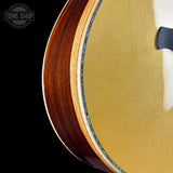 Close-up of a guitar's wooden body with a visible brand logo in the corner.