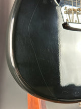 Close-up of a black guitar body with visible wear