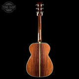 The back of an acoustic guitar with a rich, dark wood grain finish, shown against a solid black background with a Tone Shop watermark in the top left corner.