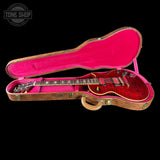 Red electric guitar in a pink-lined case with 'Tone Shop' logo.