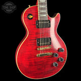 Red electric guitar with a black pickguard on a black background, featuring the Tone Shop logo.
