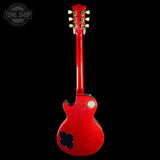 Red electric guitar with headstock on a black background, featuring 'Tone Shop' logo.