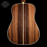 The back of an acoustic guitar featuring a rich, dark brown wood grain finish with a light cream-colored center stripe and binding, shown against a solid black background.