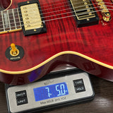 Red electric guitar on a digital scale displaying weight