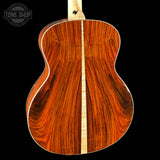 Back view of a wooden acoustic guitar with a visible brand logo in the corner.