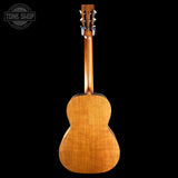 The back of a wooden acoustic guitar, showing the natural wood grain and headstock, photographed against a solid black background with a Tone Shop watermark in the top left corner.
