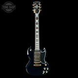 Black electric guitar with gold hardware on a black background, featuring the Gibson logo.