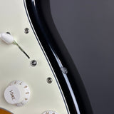 Close-up of a guitar's control knobs and headstock on a dark background