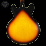 Close-up of a guitar's back with a sunburst finish on a black background, featuring 'Tone Shop' logo.