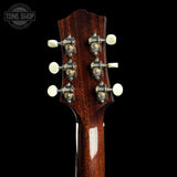 Close-up of the headstock of a guitar, showing six tuning pegs with white knobs and ornate silver-and-gold tuners on a glossy dark brown wood finish, set against a solid black background.