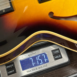 Guitar being weighed on a digital scale with a display showing weight.