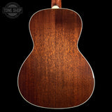 The back of a wooden acoustic guitar, showcasing a rich reddish-brown wood grain finish and white binding, set against a solid black background.